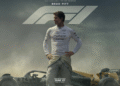 Official poster of F1 movie featuring Brad Pitt in a racing suit standing on a Formula 1 track