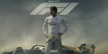 Official poster of F1 movie featuring Brad Pitt in a racing suit standing on a Formula 1 track